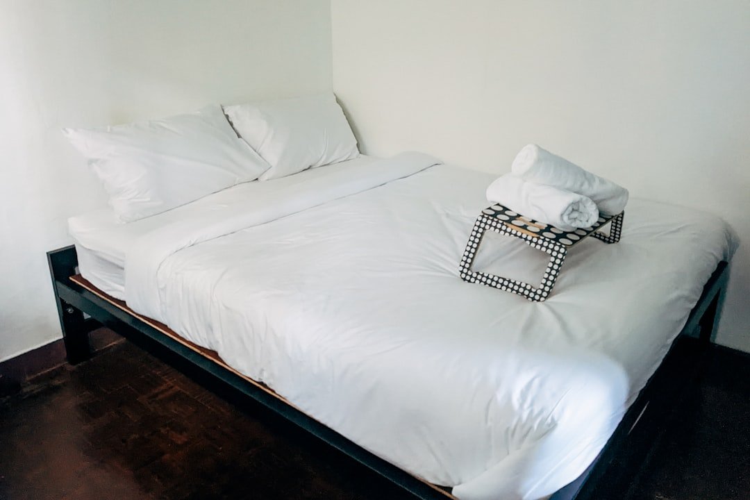 a bed with white sheets and pillows in a room