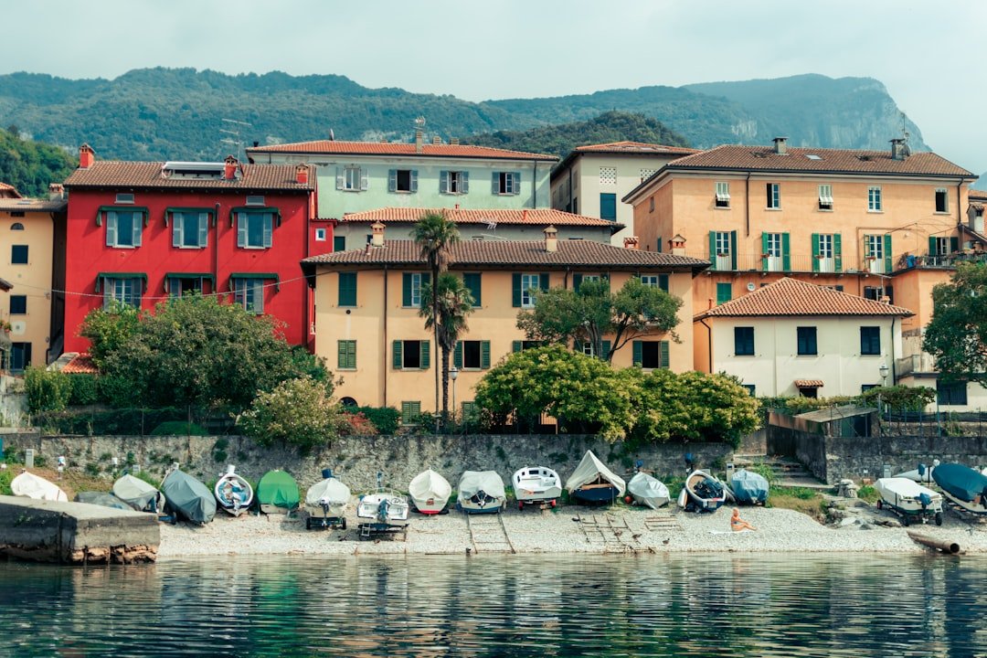 white and red boat on water near brown concrete building during daytime