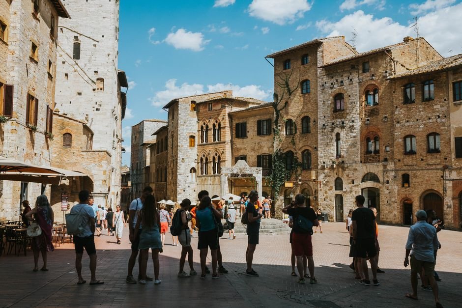 Tourists gather at the medieval Piazza della Cisterna in San Gimignano, Tuscany, Italy.