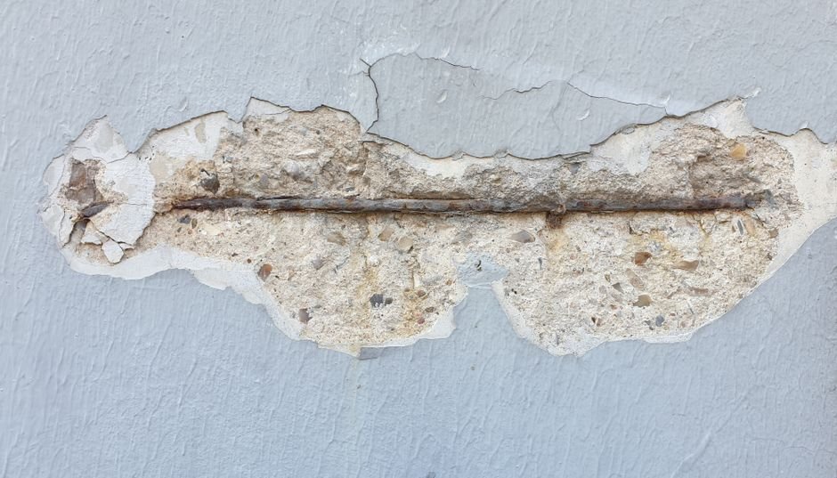 Detailed close-up of a wall with peeling paint and exposed metal bar.