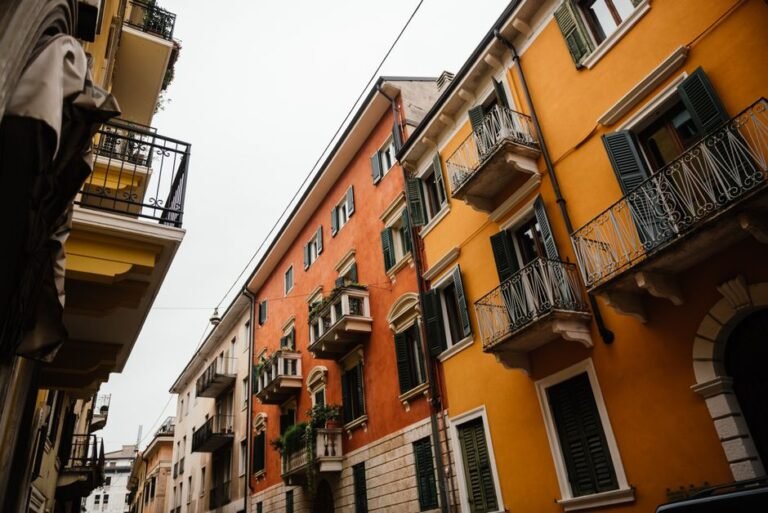 Charming narrow street with traditional Italian apartment facades featuring vibrant colors and balconies.